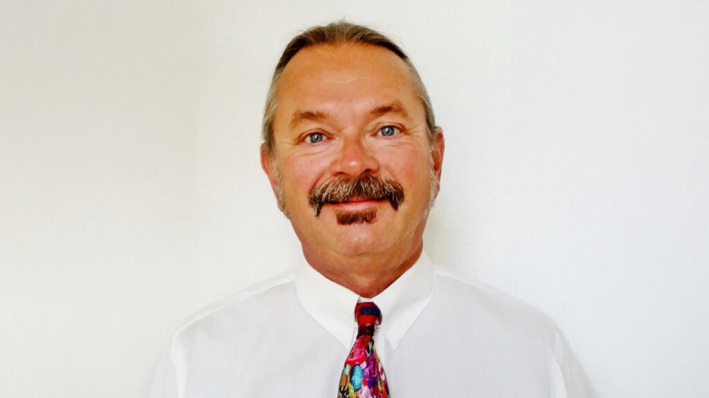 Mike Cazabon portrait wearing white shirt and colorful tie